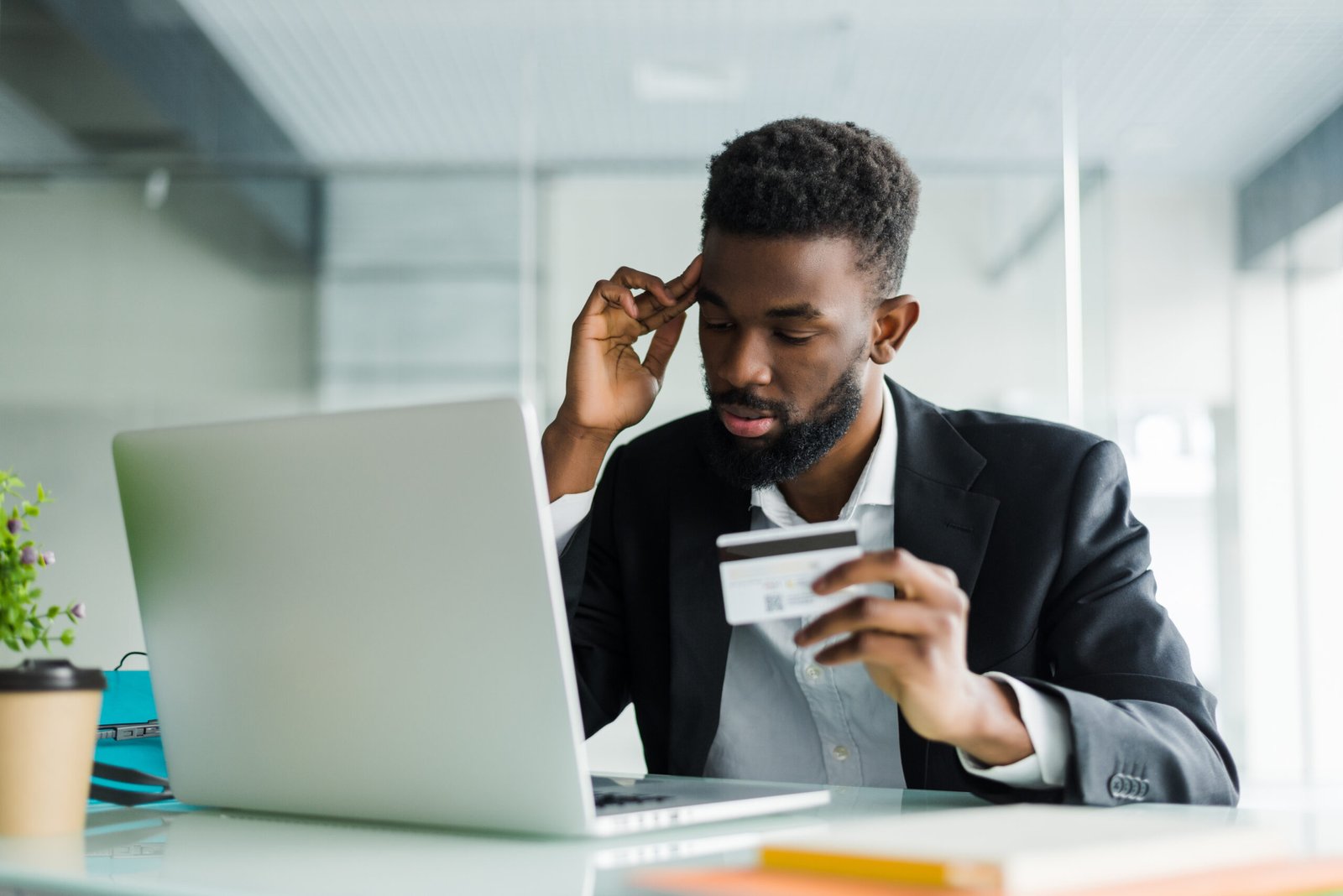 Portrait of young african man holding credit card with laptop paying via internet